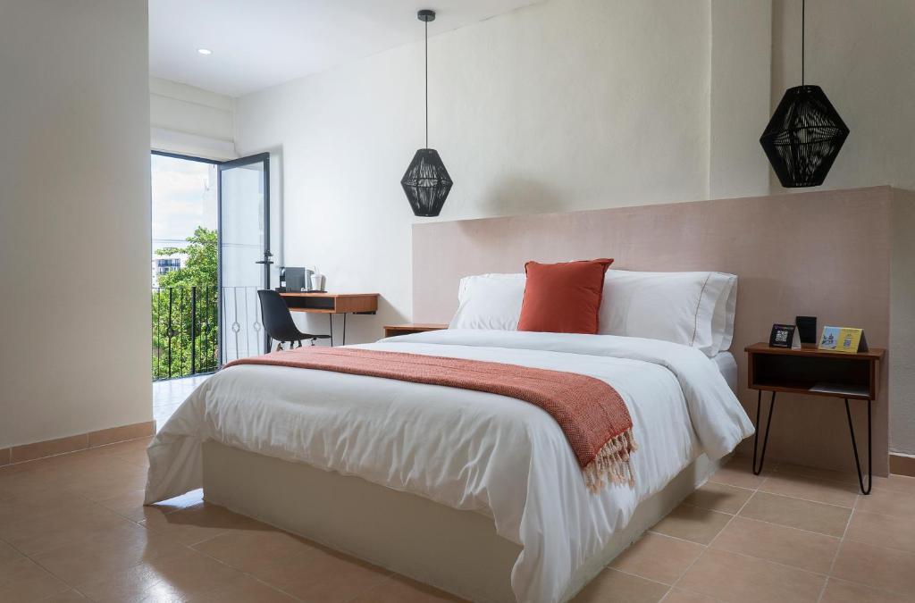ein Schlafzimmer mit Bett, Schreibtisch und Fenster in der Unterkunft Casa Rodina in Playa del Carmen