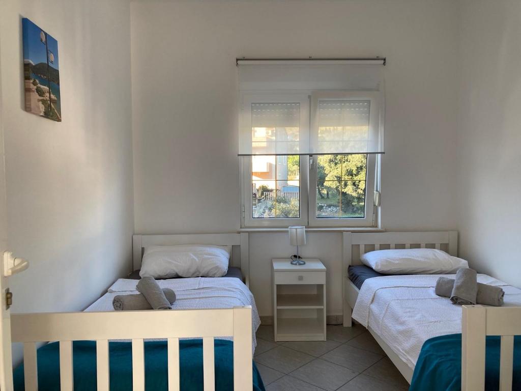two beds in a small room with two windows at Sea View Apartments in Grebaštica