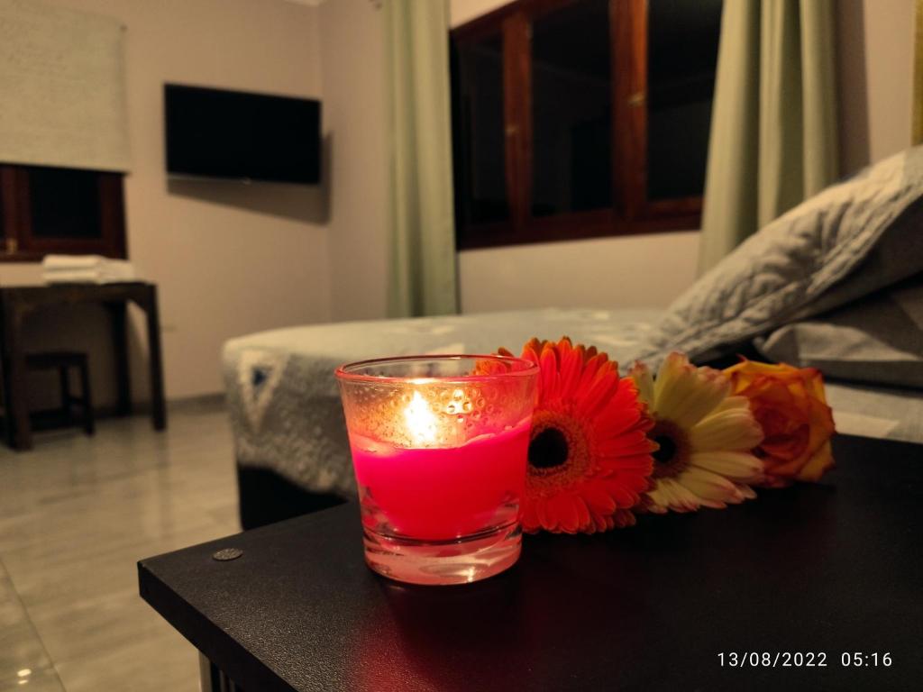 a glass with a candle on a table with a flower arrangement at Casa CORAZON DE LEÓN AQP in Arequipa