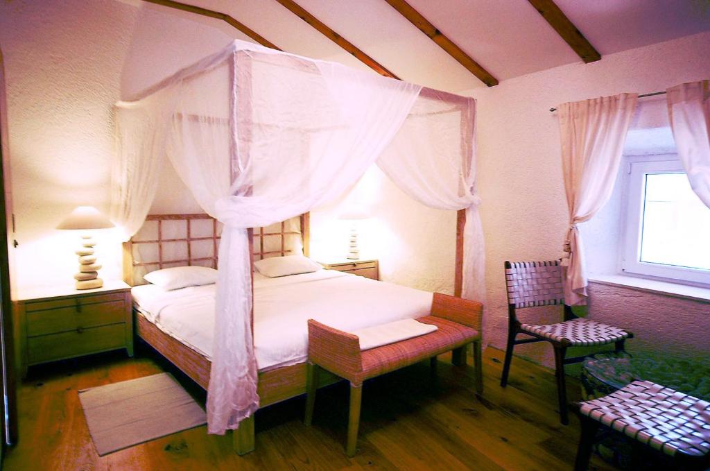 a bedroom with a canopy bed and a window at Boutique Hotel Placa in Krk