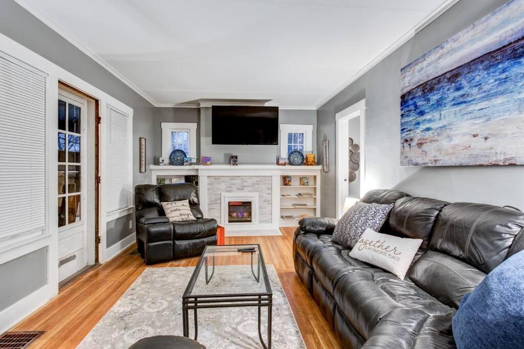 a living room with a leather couch and a fireplace at Cozy Cuse home close to downtown and University in Syracuse