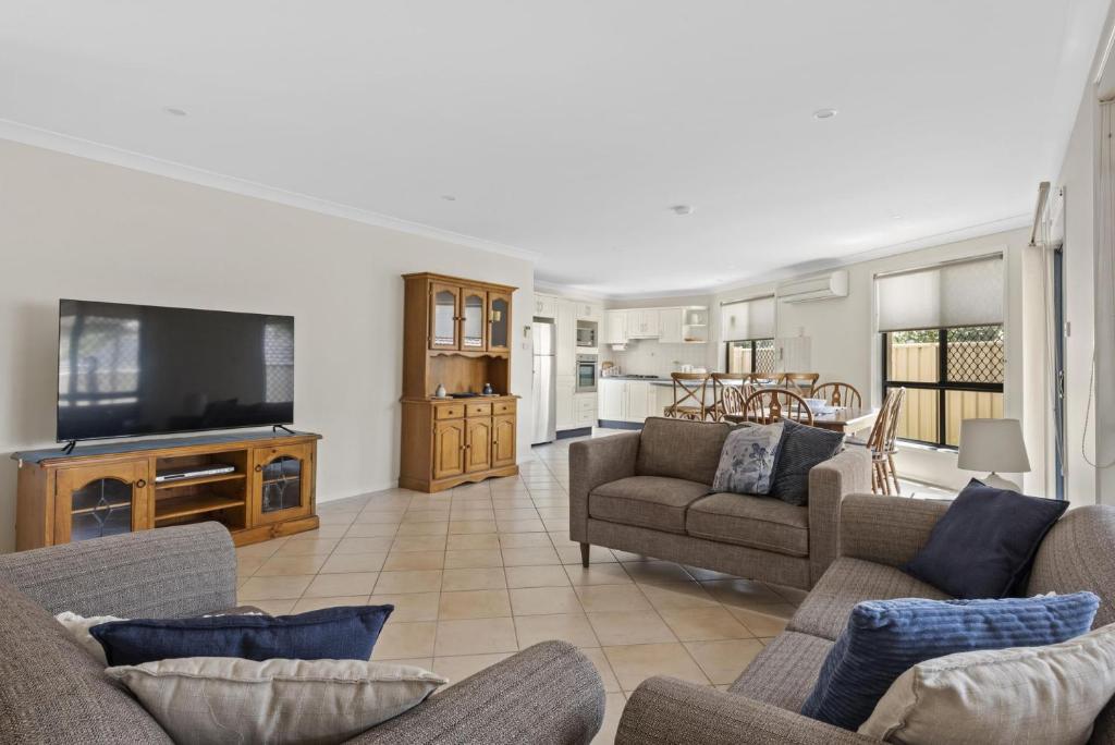 a living room with couches and a flat screen tv at Villa Serene - Belle Escapes Jervis Bay in Vincentia