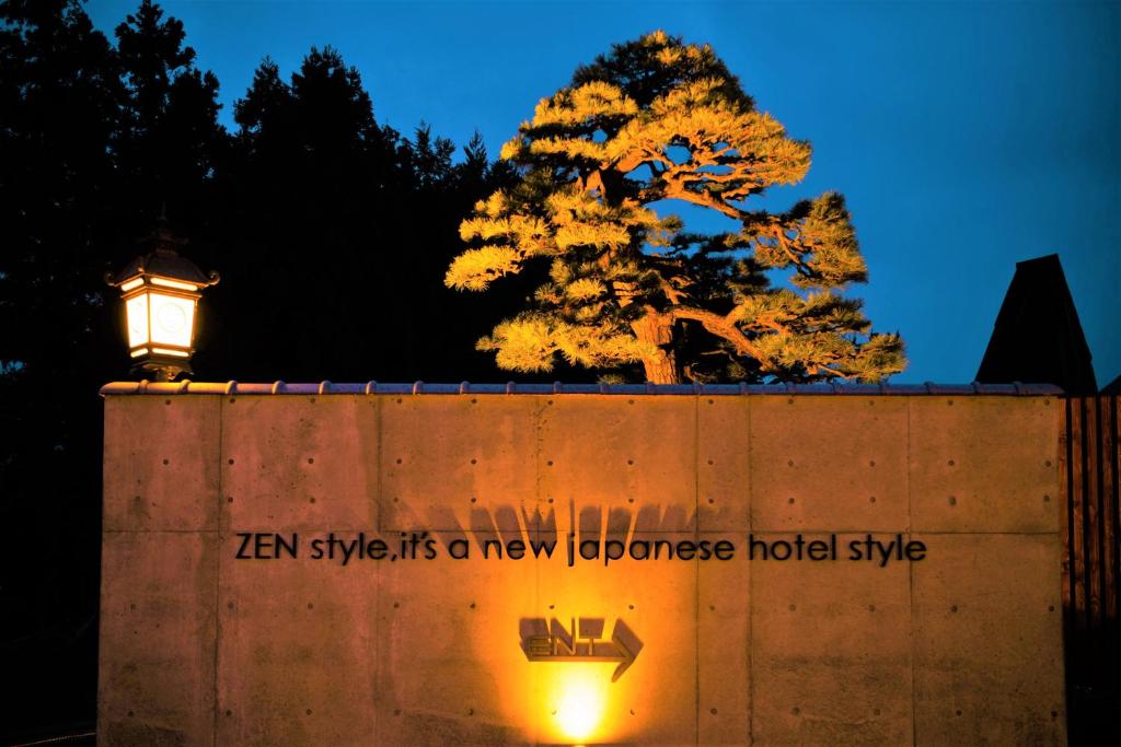 eine Wand mit einem Baum dahinter mit einem Straßenlicht in der Unterkunft HOTEL ZEN-Adult Only in Hirosaki