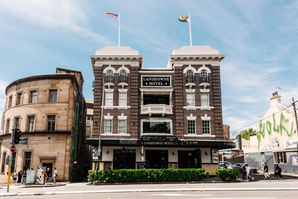 雪梨的住宿－The Lansdowne Hotel，上面有两面旗帜的砖砌建筑