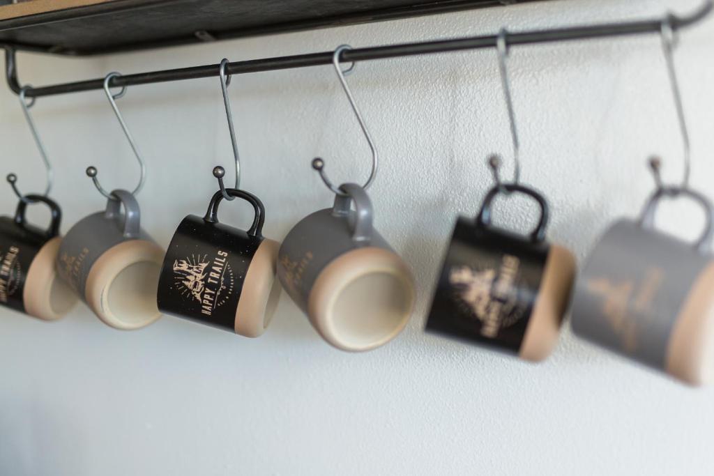 un groupe de tasses de café suspendues sur un mur dans l'établissement Happy Trails BnB, à Tropic