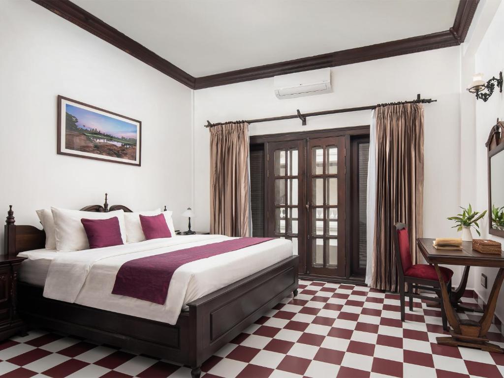 a bedroom with a bed and a checkered floor at Chateau d'Angkor La Residence in Siem Reap