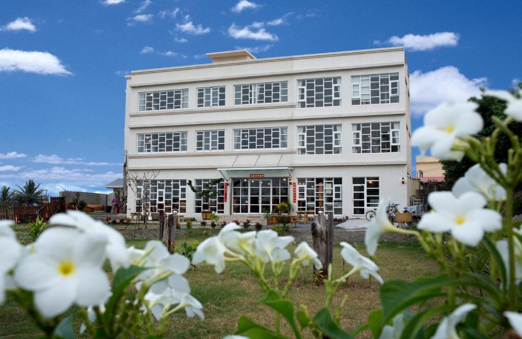 a white building with white flowers in front of it at Water Reflections at Ease in Donggang