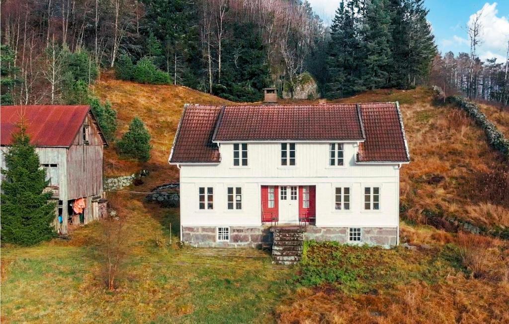 ein weißes Haus mit einer roten Tür auf einem Hügel in der Unterkunft 4 Bedroom Lovely Home In Kvinesdal in Fossdal