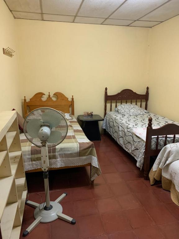 Una habitación con ventilador y una cama en una habitación en Habitación en casa Familiar en León