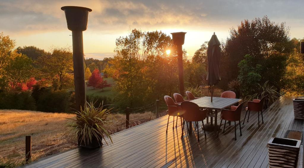 a wooden deck with a table and chairs and the sunset at The Paris Suite in Nelson
