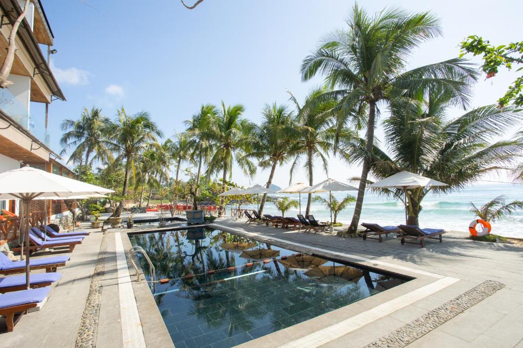 einen Pool am Strand mit Stühlen und Sonnenschirmen in der Unterkunft Palm Beach Hotel Phú Yên 