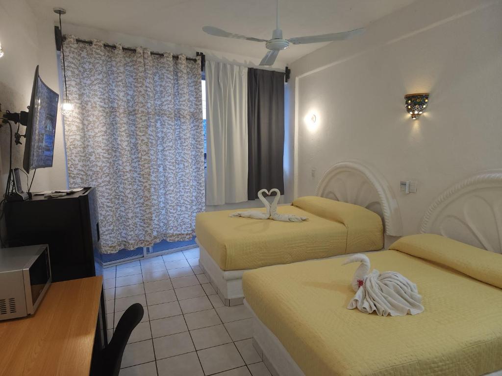 Cette chambre comprend 2 lits et une télévision. dans l'établissement Lovely studio apartment with balcony AC & wi-fi, minutes from downtown!, à Zihuatanejo