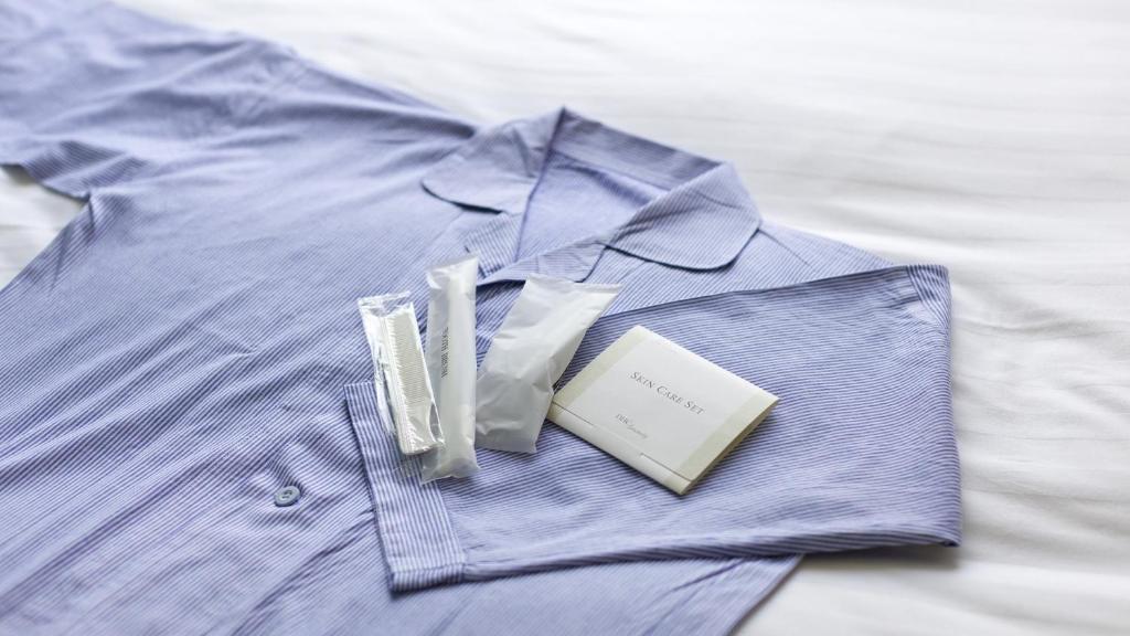 a blue shirt with a book on a bed at Toyoko Inn Osaka Itami Airport in Toyonaka
