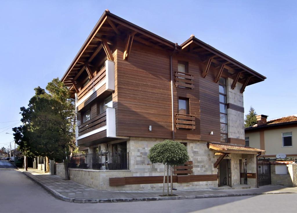 un edificio de madera con un árbol delante de él en Anita Guest House & Relax, en Perushtitsa
