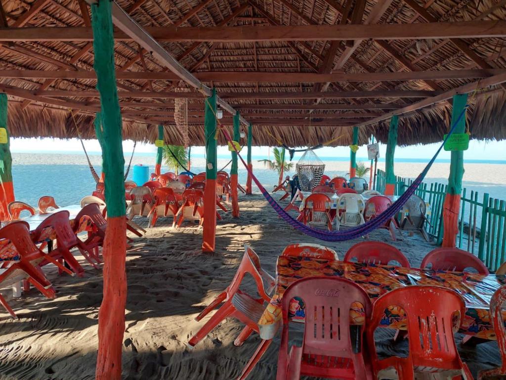 a group of chairs and tables on the beach at Barra Zacapulco - Palapa Abraham 