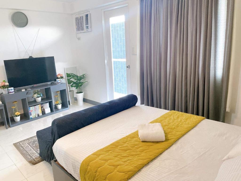 ein Schlafzimmer mit einem Bett mit einer gelben Decke darauf in der Unterkunft Spacious condominium in Davao City
