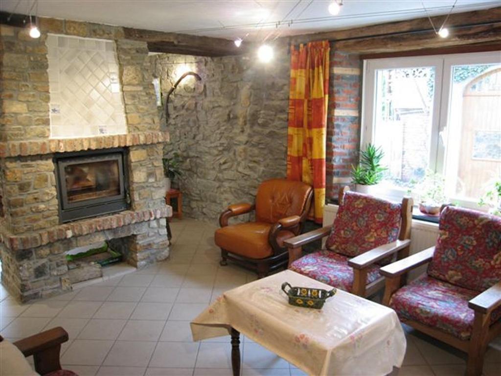 a living room with a stone fireplace and chairs at Les Bucherons in Awenne