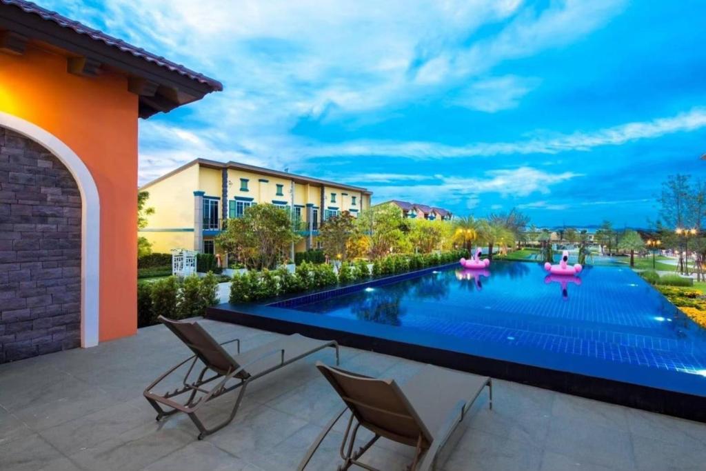 a swimming pool in a backyard with chairs and a building at โกลเด้นโฮม in Ban Map Chalut