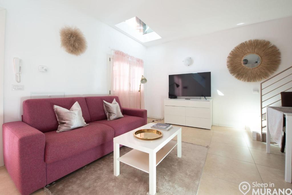 a living room with a purple couch and a tv at MURANO Place - FILIGRANA House in Murano