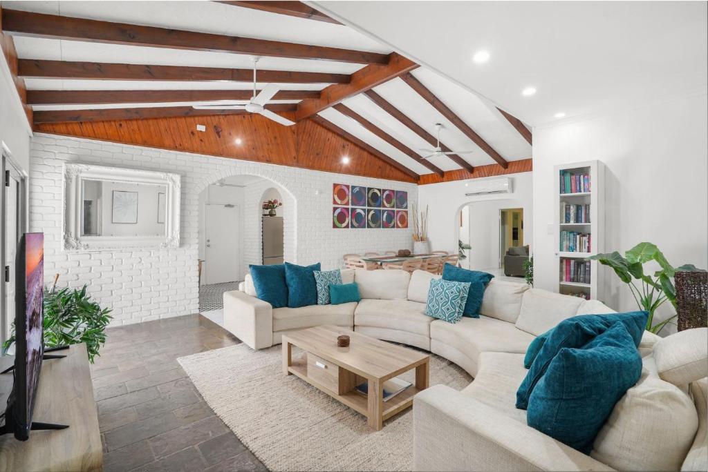 uma sala de estar com mobiliário branco e almofadas azuis em Belle Escapes Under the Mango Tree Holiday Home em Trinity Beach