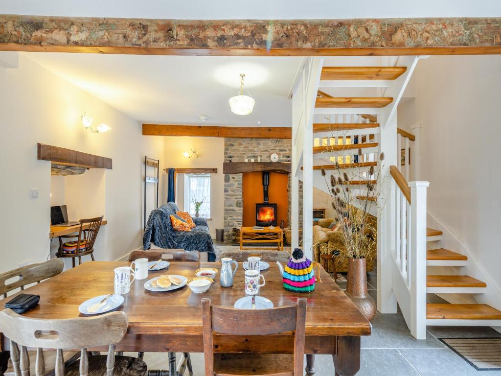 a dining room with a table and a spiral staircase at Ivy Bush Cottage in Llanddewi-Brefi