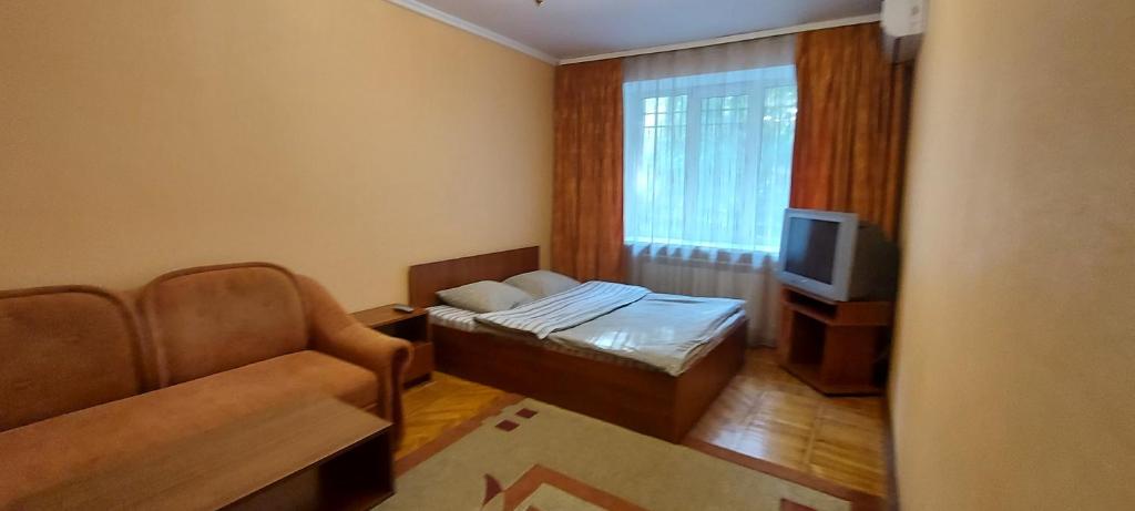 Cette petite chambre comprend un lit, un canapé et une télévision. dans l'établissement Воздухофлотский проспект, à Kiev