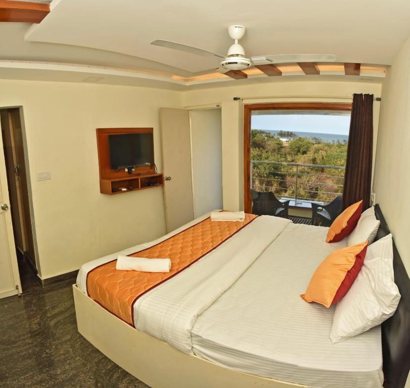 a bedroom with a bed with a television and a window at Ruthran Guest House in Mahabalipuram