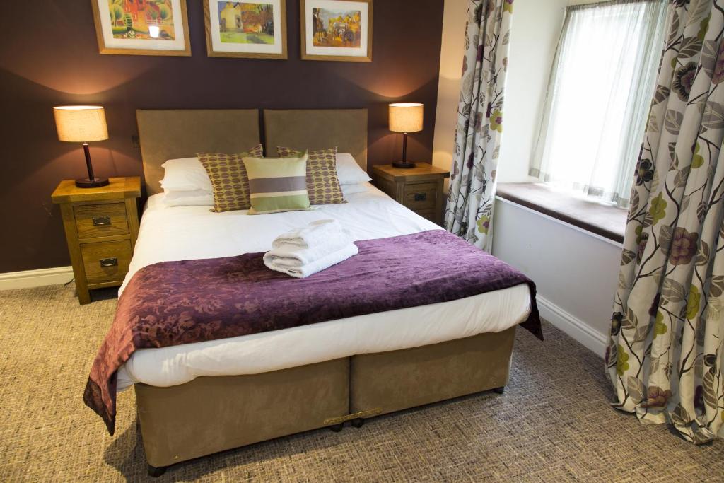 a bedroom with a bed with a purple blanket at The Colesbourne Inn in Colesbourne