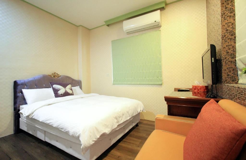 a bedroom with a bed and a tv and a chair at Lantian Baiyun in Hualien City