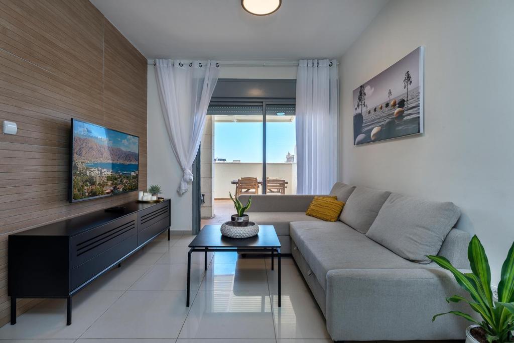 a living room with a couch and a tv at Melony Apartments Yam Suf Street in Eilat