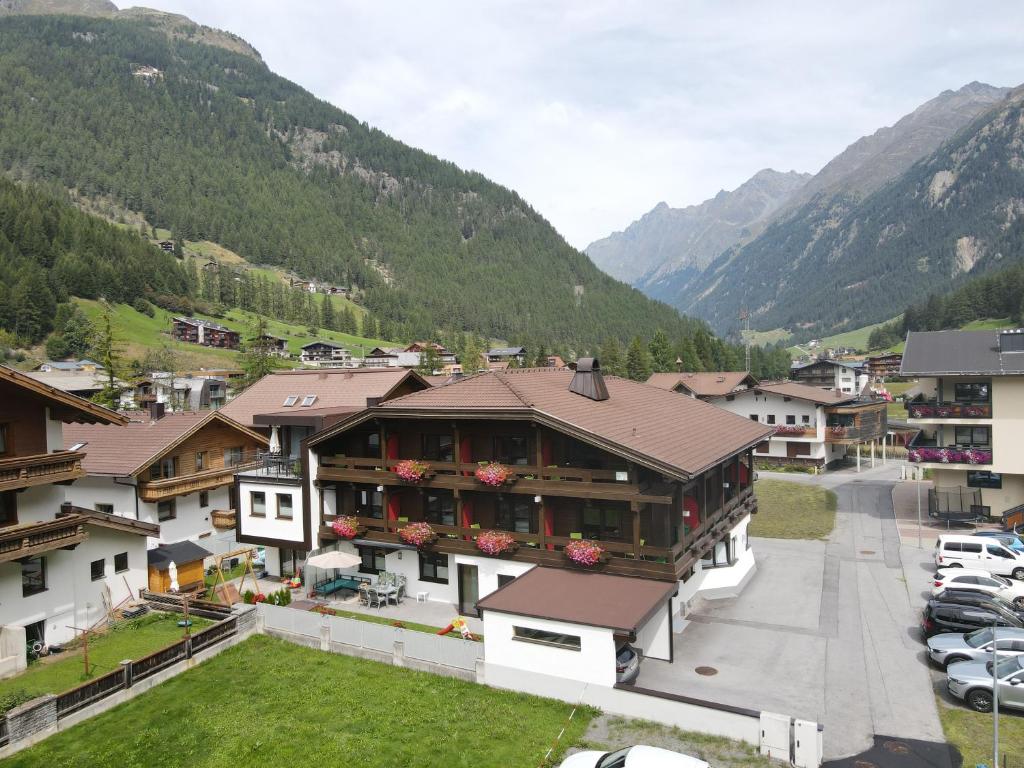 a building in a village with mountains in the background at Hotel Garni Maria Theresia in Sölden