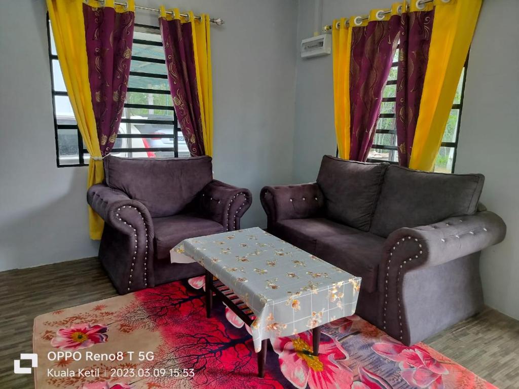 a living room with two chairs and a table at Myrol Homestay Kuala Ketil in Kuala Ketil