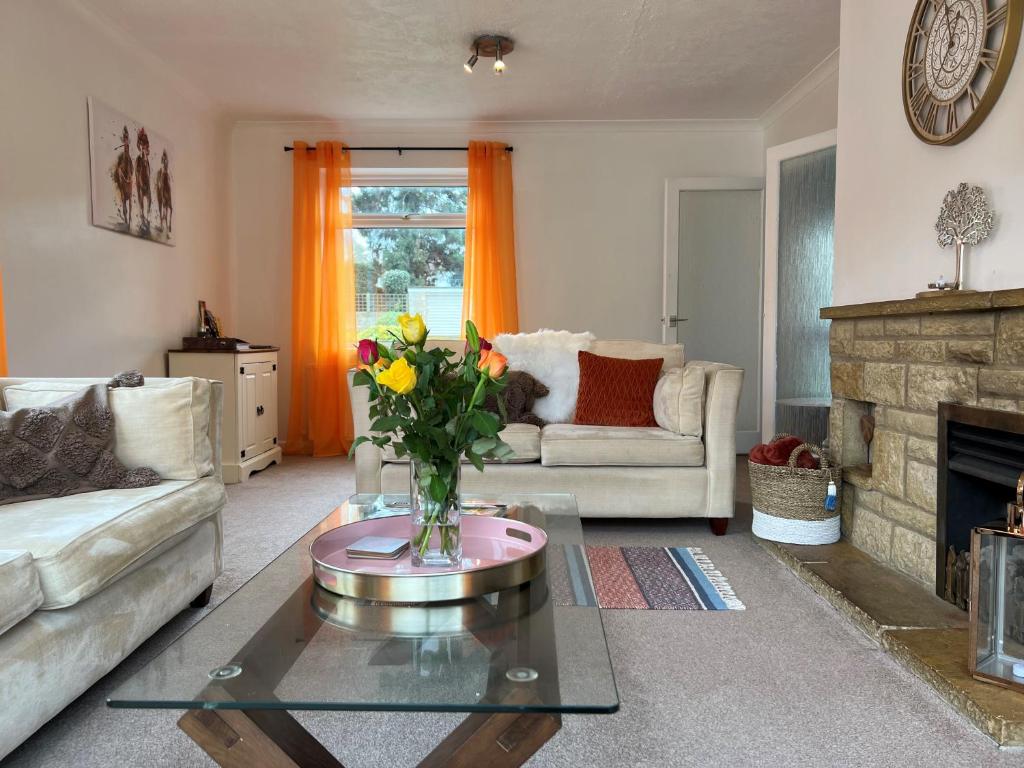 Una sala de estar con un jarrón de flores sobre una mesa. en Charming 4-Bed House in Cheltenham Free Parking, en Cheltenham