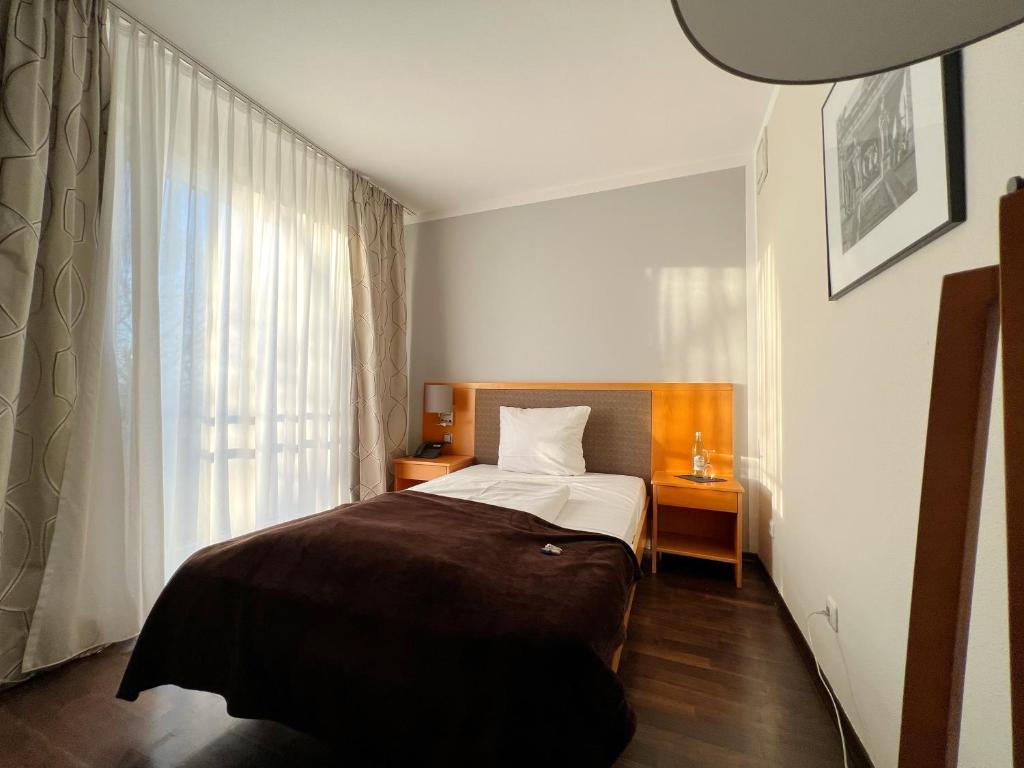 a small bedroom with a bed and a window at Hotel Prinz in Munich