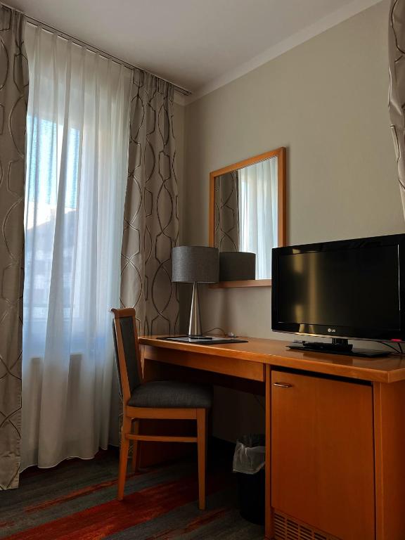 a desk with a television and a chair in a room at Hotel Prinz in Munich