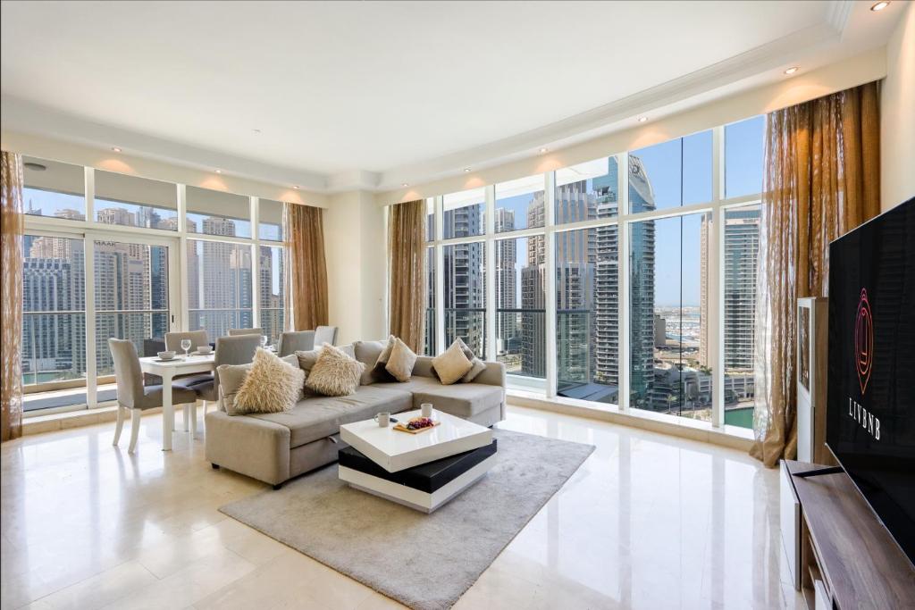 a living room with a couch and a tv and large windows at Dubai Marina 3 Bedroom Suite with Full Marina View in Dubai