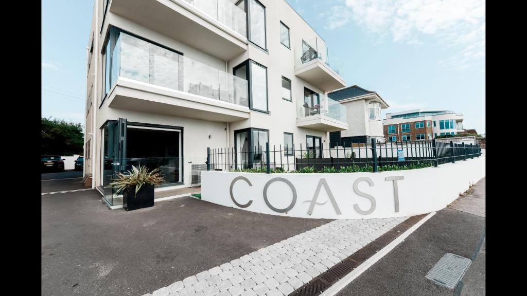 een wit gebouw met een bord dat kust leest bij Brand New Beachfront Ground floor with garden 2 Bed apartment 6 Guests in Bournemouth