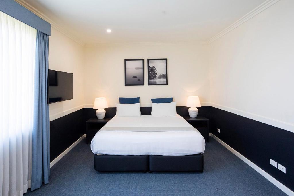 um quarto de hotel com uma cama e duas lâmpadas em Hawkesbury Race Club Motel em Windsor