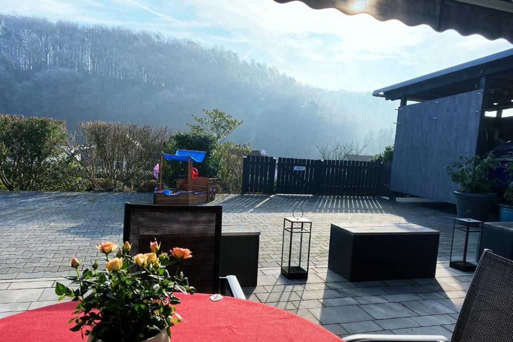 un patio con una mesa y sillas rojas y una montaña en Ferienwohnung Ricke, en Krombach