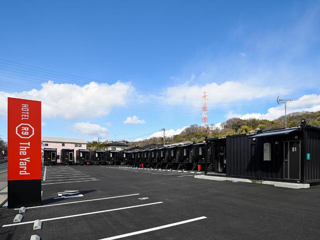 HOTEL R9 The Yard Fukuyama في فوكوياما: موقف للسيارات مع صف من الحاويات السوداء