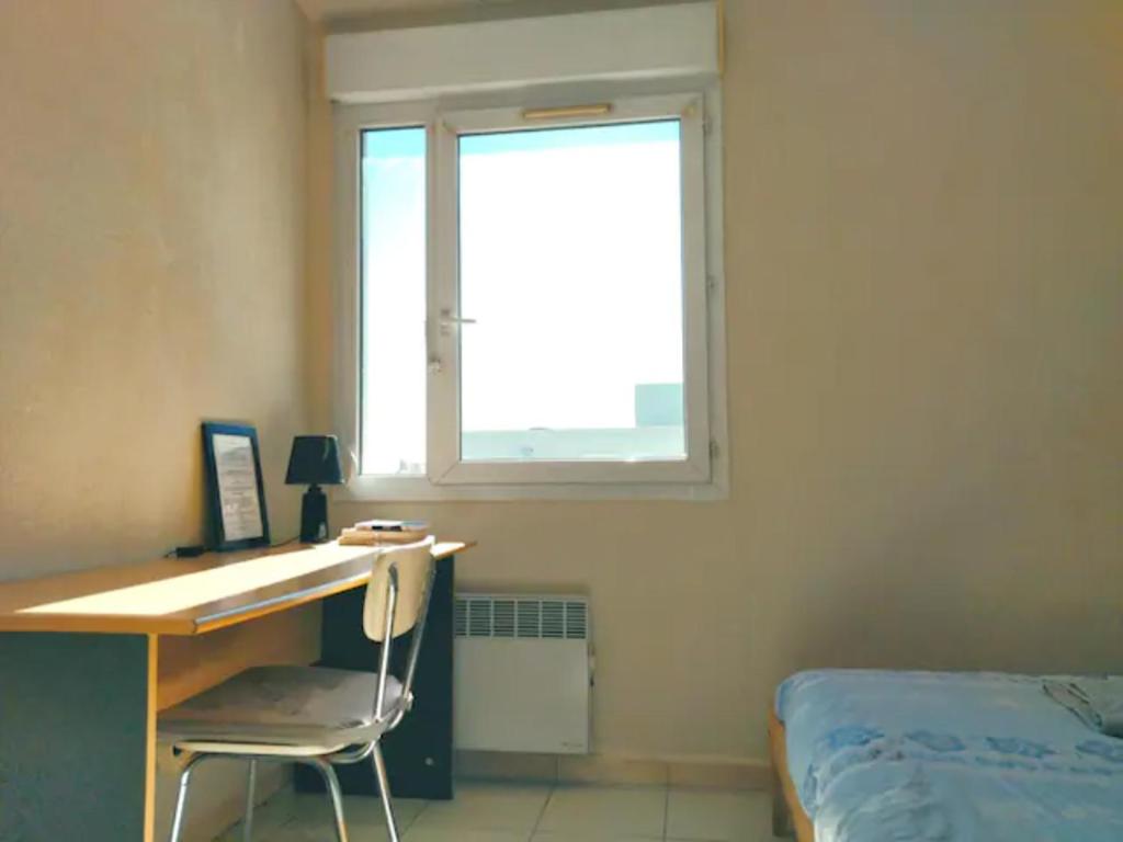 a bedroom with a desk and a bed and a window at Au cœur du grand Lyon à côté de la gare Part-Dieu in Villeurbanne