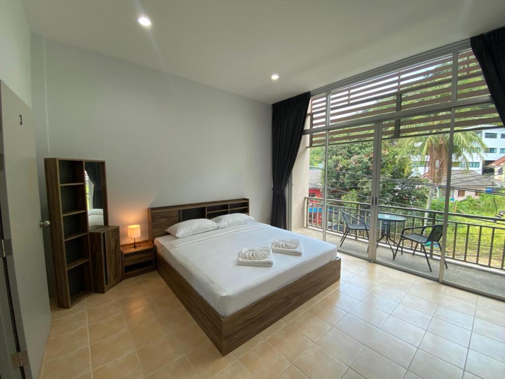 L&P Guesthouse في شاطئ كاتا: غرفة نوم بسرير ونافذة كبيرة