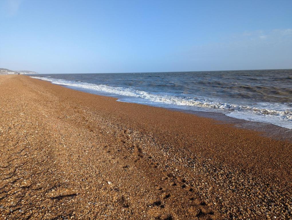 einen Strand mit Fußabdrücken im Sand und im Ozean in der Unterkunft Beautiful house next to Beach & Park nr Zoo Newly refurbished in Kent