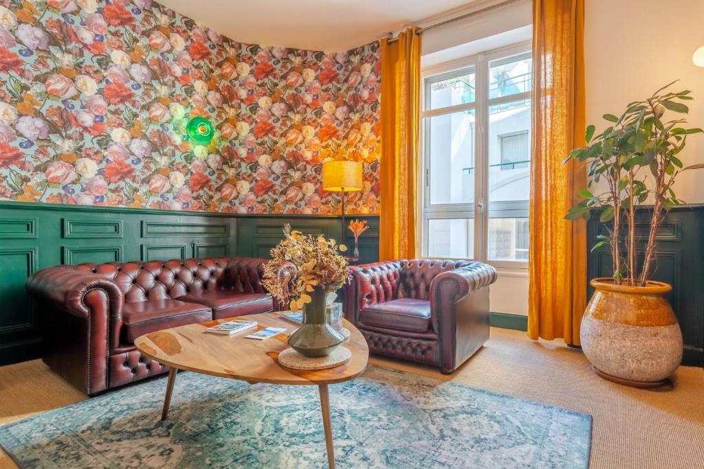ein Wohnzimmer mit einem Sofa und einem Tisch in der Unterkunft Ama Hôtel in Biarritz