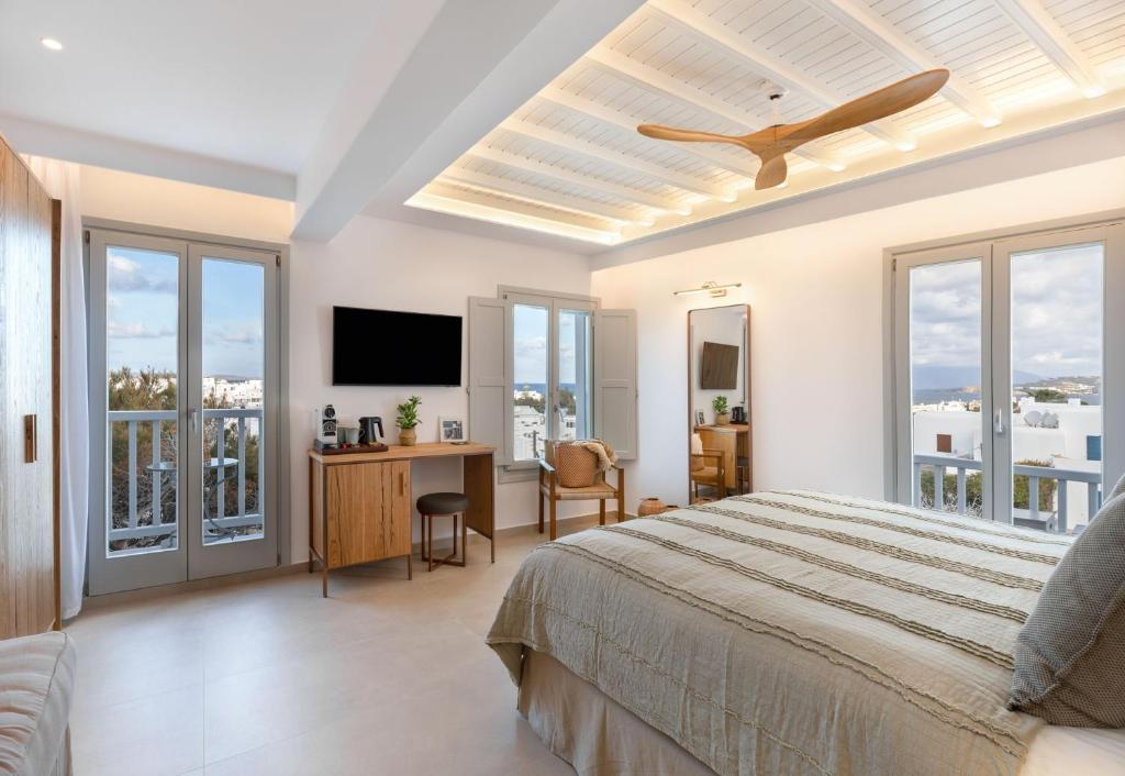 a bedroom with a bed and a desk with a tv at Elena Hotel Mykonos in Mýkonos City
