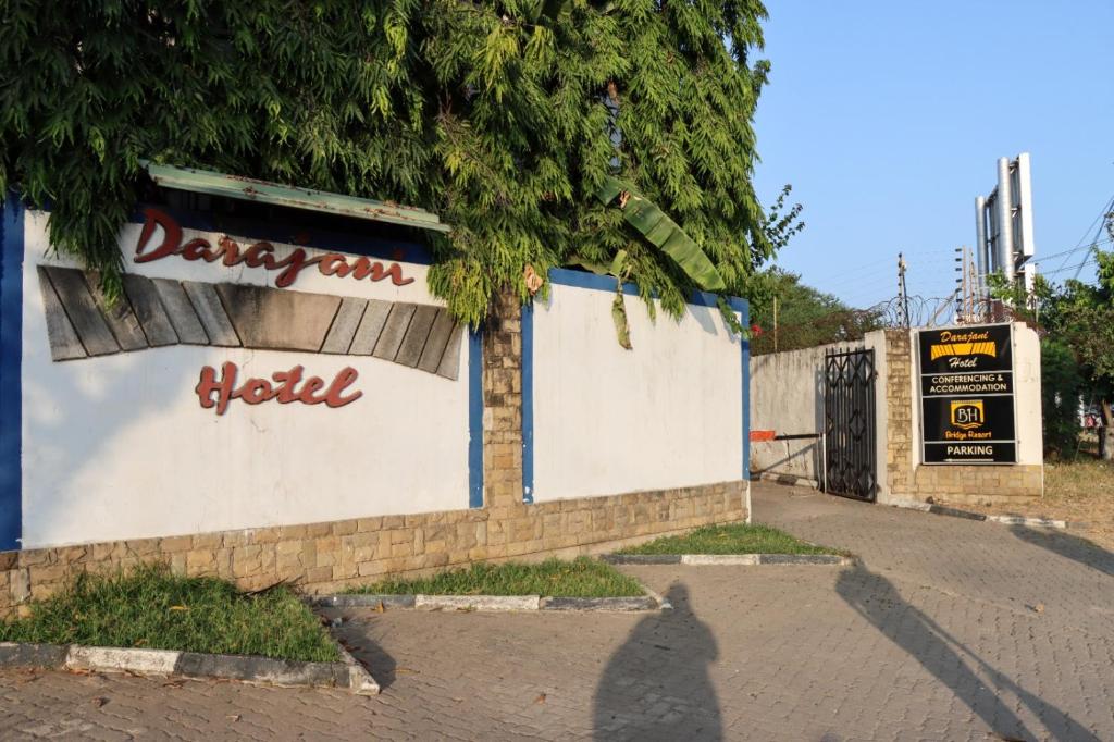 Darajani Hotel في مومباسا: شخص واقف بجانب جدار عليه لافته