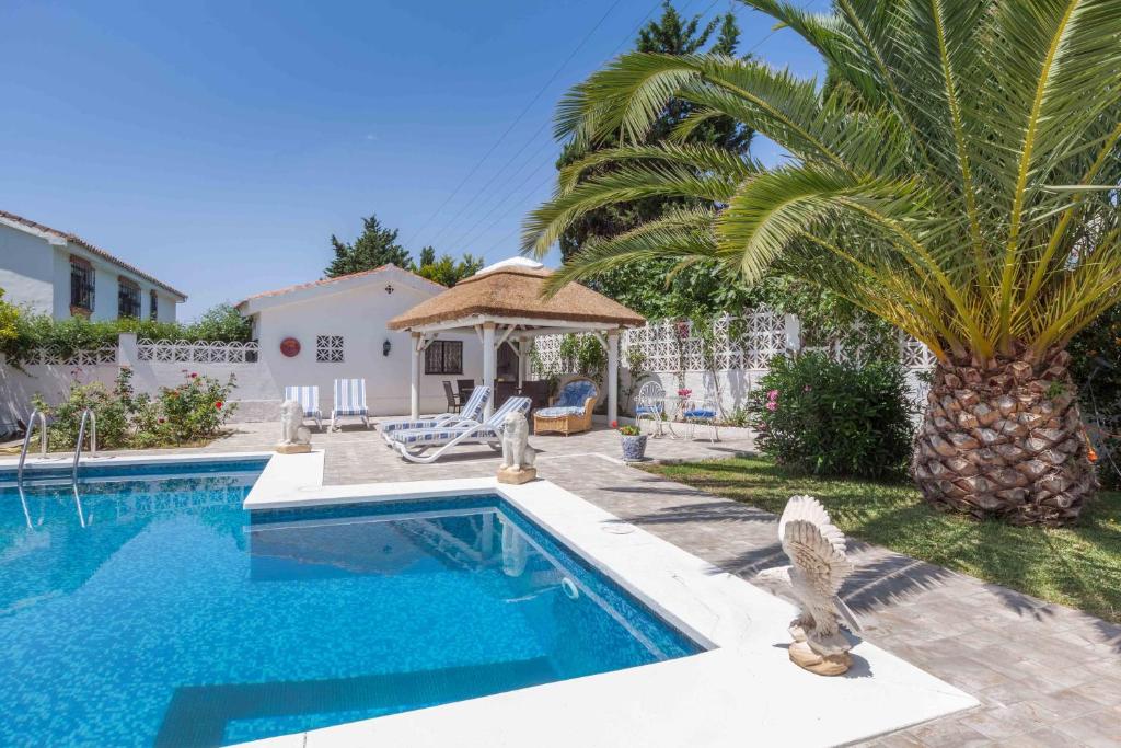 a swimming pool with a palm tree and a house at Stunning Villa with private pool Ref 30 in Santa Fe de los Boliches