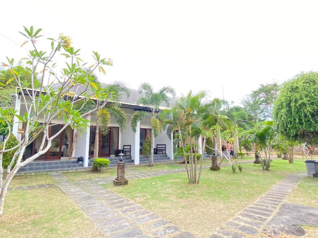 a white house with palm trees in front of it at Padang-Padang Sari Homestay in Uluwatu