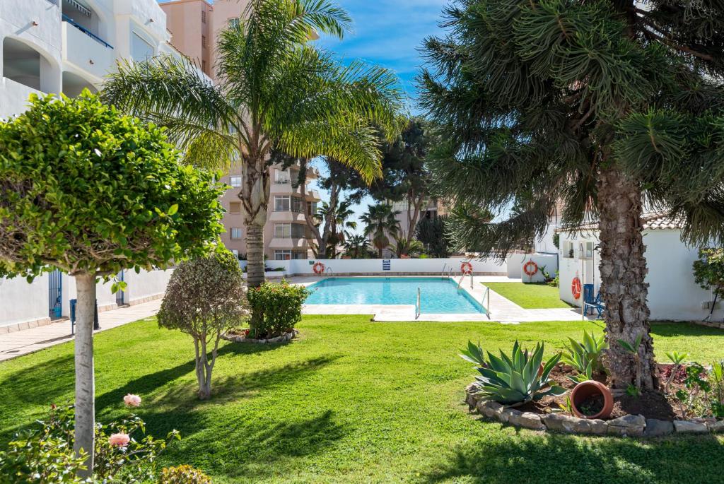 een tuin met een zwembad en palmbomen bij Marysol beachclose apartment with pool Ref 200 in Benalmádena