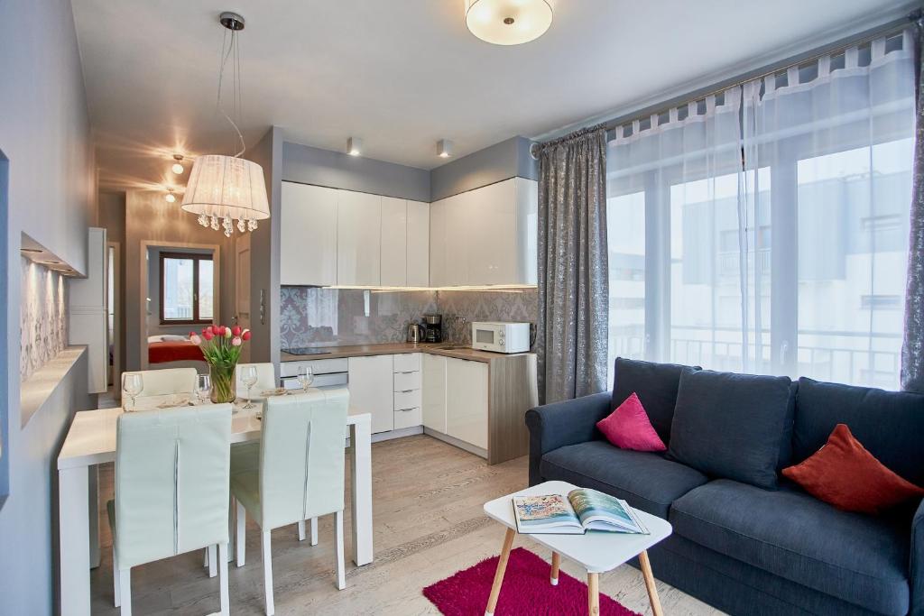 a living room with a blue couch and a kitchen at Świnoujście Platan, Sun & Snow in Świnoujście